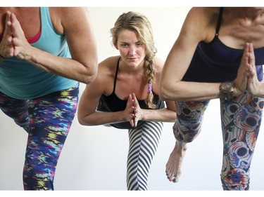 Paula Munoe (striped pants), co-owner of Yoga Town in Little Italy, leads a hot yoga class at her studio.