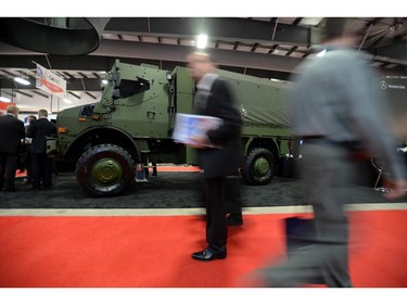 People make their way past a display of a armoured vehicle at the CANSEC trade show in Ottawa on Wednesday, May 28, 2014. The bombs and mortars on display are models.