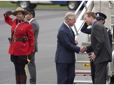 A Royal Canadian Mounted Police officer salutes as Prince Charles is greeted by Justice Minister Peter MacKay at the airport in Halifax at the start a four-day tour of three provinces on Sunday, May 18, 2014. This is Charles' 17th visit to Canada.