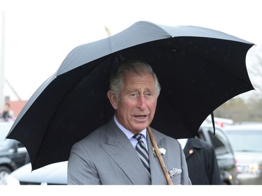 Prince Charles shields himself from the rain in Cornwall, P.E.I. on Tuesday, May 20, 2014.