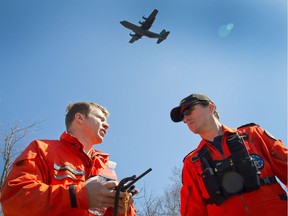 SAR Techs Sgt Eric Soubriere, left, and M/Cpl Steve Delage confer while a Hercules circles overhead as personnel from 424 (Transport and Rescue) Squadron conducted a search and rescue (SAR) exercise called TIGEREX 2014 at Mont Cascades ski hill in Gatineau, Quebec.