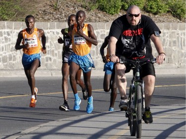 The top men 10k runners, including the winner Wilson Kiprop, run past a cyclist by the Rideau Canal at the Ottawa Race Weekend on Saturday May 24, 2014. (Patrick Doyle / Ottawa Citizen)  ORG XMIT: 0526 ottawa10k21