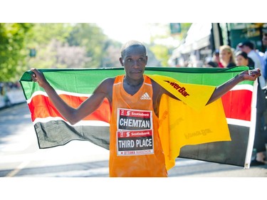 Third place marathon finisher Ishhimael Bushendich Chemtan with the Kenyan flag at the finish line at Ottawa Race Weekend Sunday May 25, 2014.