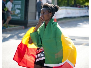 Tigist Tufa wraps in the Ethiopian flag after crossing the finish line as the top woman in the marathon at  Ottawa Race Weekend Sunday May 25, 2014.