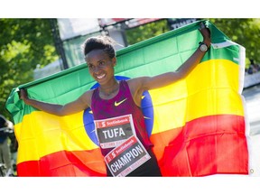 Tigist Tufa celebrates with the Ethiopian flag after crossing the finish line first in the women's marathon on Sunday, May 25, 2014.