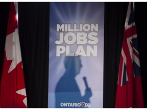 The silhouette of Ontario Progressive Conservative Leader Tim Hudak is cast on a campaign poster as he delivers a speech in Toronto on Wednesday, May 14.
