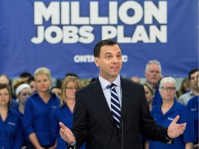 Ontario PC leader Tim Hudak is surrounded by his message as he speaks to the media at a campaign stop inside an electronics retail store in London, Ont., Thursday, May 15, 2014.