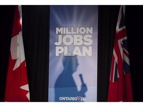 The silhouette of Ontario PC Leader Tim Hudak is cast on a campaign poster as he delivers a speech in Toronto on Wednesday, May 14.