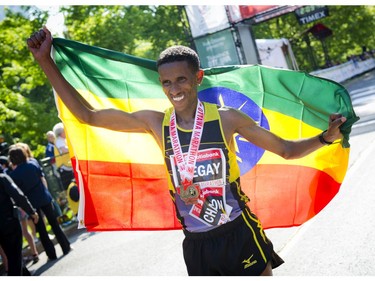 Yemane Tesgay wraps the Ethiopian flag around him in front of cameras after finishing first place in the marathon at Ottawa Race Weekend Sunday May 25, 2014.