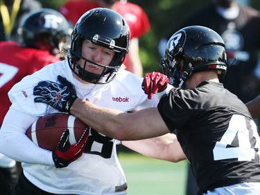 Jordan Roberts (L) is tackled by  Jason Pottinger during the opening day of the Ottawa RedBlacks training camp, June 01, 2014.
