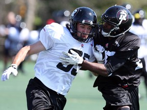 Garret Burgess, left, is tackled by Brandyn Thompson during the opening day of the Ottawa RedBlacks training camp, June 1, 2014.