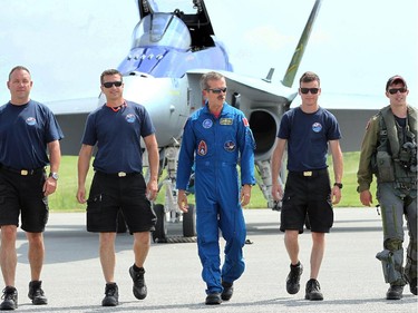 10.51 a.m. Former astronaut Chris Hadfield, centre, walks across the Gatineau airstrip with Captain Adam "Manik" Runger, far right, and others from the CF-18 Demo Team following the fighter jet's arrival at the Vintage Wings of Canada event, held Monday, June 30, 2014 at the Gatineau Airport.