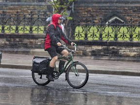 A cyclist at Wellington at Elgin streets as Ottawa received warm wet weather on Tuesday, with temperatures in the low 20s C with a chance of fog later in the evening.