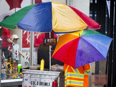 A pedestrian passes a hot dog cart at Metcalfe near Sparks streets as Ottawa received warm wet weather on Tuesday, with temperatures in the low 20s C with a chance of fog later in the evening.