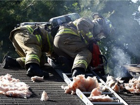 Firefighters work on putting out smoking embers in the roof of a home that was gutted by a fire at 5 Bell Street in Stittsville Tuesday morning