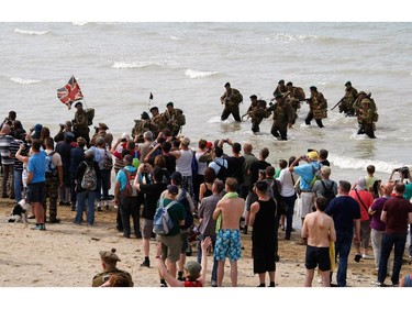 A group of military re-enactors feign a landing of a World War II barge,  on the beach  of Arromanches, France,  Friday, June 6, 2014, as part of D-Day commemorations. World leaders and veterans gathered by the beaches of Normandy on Friday to mark the 70th anniversary of World War Two's D-Day landings.