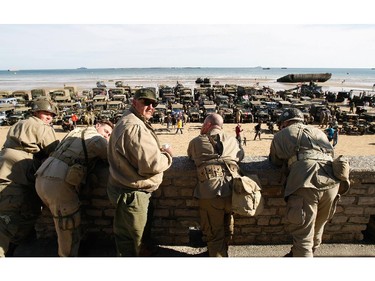 A group of military re-enactors look at the World War II vehicles displayed on the beach  of Arromanches, France,  Friday, June 6, 2014, as part of D-Day commemorations. World leaders and veterans gathered by the beaches of Normandy, northern France on Friday to mark the 70th anniversary of the World War II D-Day landings.