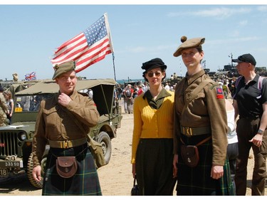 A group of military re-enactors walk on the beach of Arromanches, France,  where World War II vehicles are displayed,  Friday, June 6, 2014, as part of D-Day commemorations. World leaders and veterans gathered by the beaches of Normandy on Friday to mark the 70th anniversary of World War Two's D-Day landings.