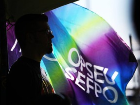 A man is silhouetted against a fluttering OPSEU flag at a rally out front of the Ottawa-Carleton Detention Centre on Thursday, June 26, 2014. (Cole Burston/Ottawa Citizen)