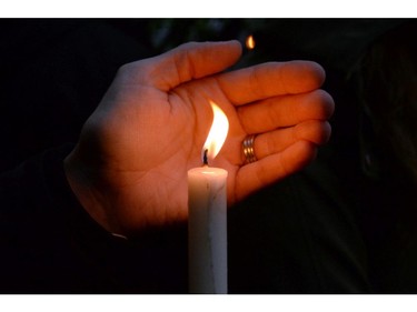 A person hold a candle as people take part in a candlelight vigil outside RCMP headquarters in Moncton, N.B., on Friday, June 6, 2014. RCMP say a man suspected in the shooting deaths of three Mounties and the wounding of two others in Moncton was unarmed at the time of his arrest early Friday and was taken into custody without incident.