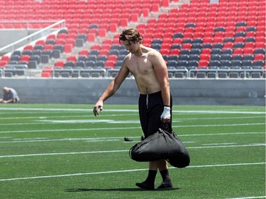 A player carries a bag of sand back and forth across the field following practice for strength training. The Ottawa Redblacks held their first practice ever at the new TD Place stadium at Lansdowne Park Friday, June 27, 2014.