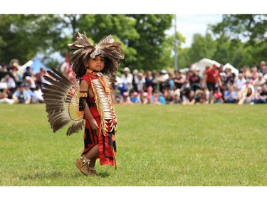 A youngster in traditional regalia wanders about at the Summer Solstice Aboriginal Festival at Vincent Massey Park on Saturday.