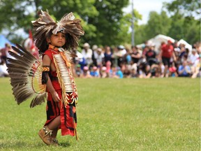 A youngster in traditional regalia wanders about at the Summer Solstice Aboriginal Festival at Vincent Massey Park.