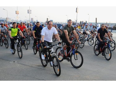 In this photo provided by Egypt's state news agency MENA, Egyptian President Abdel-Fattah el-Sissi, center, rides a bike in a cycling event in Cairo, Egypt, Friday, June 13, 2014. El-Sissi rode 18.7 kilometers (11.6 miles) along with those including college students, cyclists and security forces members on Cairo streets, according to the agency's statement.