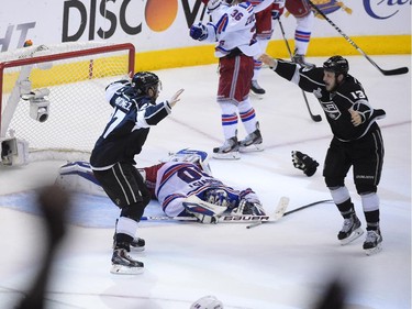 Los Angeles Kings defenseman Alec Martinez, left, and teammate left wing Kyle Clifford celebrate as New York Rangers goalie Henrik Lundqvist, of Sweden, lies on the ice after the Kings beat the Rangers overtime in Game 5 of the NHL Stanley Cup Final series Friday, June 13, 2014, in Los Angeles.