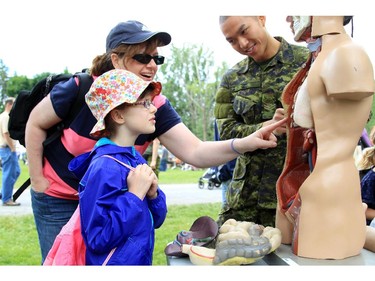 Alex Becke, 7, and her mother, Julie johnstone, get an anatomy lesson from Cpl. Daniel Ngo, a medic with the 28th Field Ambulance, at the CHEO Teddy Bear pinic at Rideau Hall on Saturday.