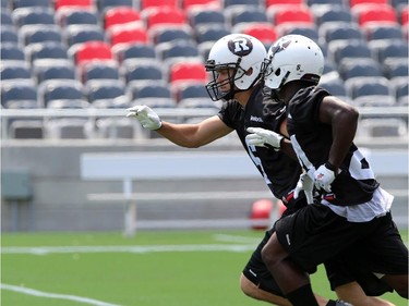 Antoine Pruneau #6 (L) and Jerrell Gavins #24 (R), of the Ottawa Redblacks run during a practice at TD Place stadium in Ottawa on June 29, 2014.