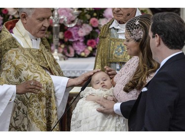 Archbishop Anders Wejryd, left, baptizes Princess Leonore held by her mother Princess Madeleine and father Christopher O'Neill, right, during the christening ceremony in the Drottningholm Palace church outside Stockholm, Sweden, Sunday, June 8, 2014.