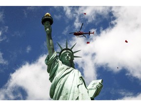 NEW YORK, NY - JUNE 06: A helicopter drops rose petals over the Statue of Liberty during the Commemorating 70th Anniversary of D-Day on June 06, 2014 in New York City.