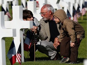 Michel Colas (C) shows his grandsons Samuel Colas (L) and Rafael Schneider (R) the Normandy American Cemetery before the start of an official event with U.S. President Barack Obama on Friday June 6, 2014 in Colleville-sur-Mer, France.