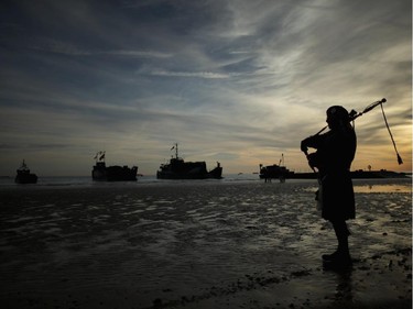 ARROMANCHES LES BAINS, FRANCE - JUNE 06: A piper plays a lament on Gold Beach as landing craft from the Royal Marines arrive at Arromanche on June 6, 2014 in Arromanches Les Bains, France.  Friday 6th June is the 70th anniversary of the D-Day landings which saw 156,000 troops from the allied countries including the United Kingdom and the United States join forces to launch an audacious attack on the beaches of Normandy, these assaults are credited with the eventual defeat of Nazi Germany. A series of events commemorating the 70th anniversary are planned for the week with many heads of state travelling to the famous beaches to pay their respects to those who lost their lives.