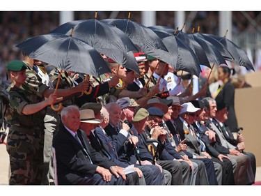 OUISTREHAM, FRANCE - JUNE 06:  D-day veterans are shielded by umbrellas from the sun at the main international ceremony commemorating the 70th anniversary of the D-Day invasion with 17 heads of state at Sword Beach on June 6, 2014 at Ouistreham, France. Friday the 6th of June is the 70th anniversary of the D-Day landings that saw 156,000 troops from the Allied countries, including the United Kingdom and the United States, join forces to launch an audacious attack on the beaches of Normandy,  these assaults are credited with the eventual defeat of Nazi Germany. A series of events commemorating the 70th anniversary are planned for the week with many heads of state travelling to the famous beaches to pay their respects to those who lost their lives.
