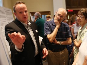 Byron Hemlow, left, explains the transportation plan surrounding Lansdowne Park to Ferdinand Roblofs, second from left, and others at the Glebe Community Centre on Tuesday, June 17, 2014.