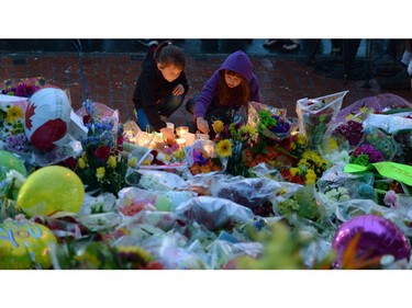 Children take part in a candlelight vigil outside RCMP headquarters in Moncton, N.B., on Friday, June 6, 2014. RCMP say a man suspected in the shooting deaths of three Mounties and the wounding of two others in Moncton was unarmed at the time of his arrest early Friday and was taken into custody without incident.