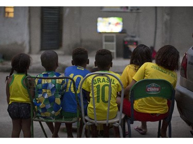 Children watch the World Cup opening match between Brazil and Croatia in an alley at the Mangueira slum, in Rio de Janeiro, Brazil, Thursday, June 12, 2014. After taking the early lead in the opening match of the international soccer tournament, Croatia fell 3-1 to the five-time champion Brazil.