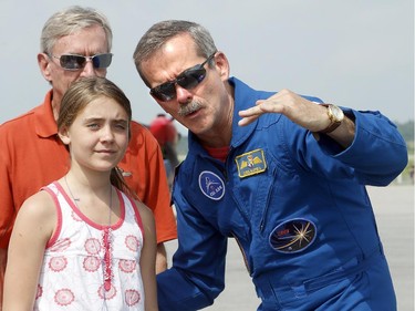 Chris Hadfield explains the elements of a fighter jet to Vintage Wings founder, Mike Potter, and his 11-year-old daughter, Lilli, on Monday, June 30, 2014.