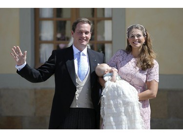 Christopher O'Neill, left, wves to the crowds as Princess Leonore is held by her mother, Princess Madeleine, right, outside the church after the christening ceremony in the Drottningholm Palace church outside Stockholm, Sweden, Sunday, June 8, 2014.