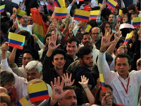 Supporters of Colombian President Juan Manuel Santos show the palms of their hands reading "Peace."