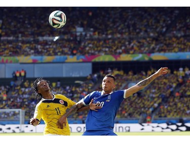 Colombia's Juan Cuadrado, left, is challenged by Greece's Jose Holebas during the group C World Cup soccer match between Colombia and Greece at the Mineirao Stadium in Belo Horizonte, Brazil, Saturday, June 14, 2014.