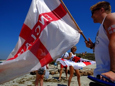 English fans hold England flags as they walk on "Nissi Beach"  in the famous southeastern coastal resort of Ayia Napa, Cyprus, Saturday, June 14, 2014.  England will play today against Italy in 2014 World Cup in Brazil.