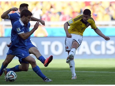 Colombia's midfielder James Rodriguez (R) shoots and scores during a Group C football match between Colombia and Greece at the Mineirao Arena in Belo Horizonte during the 2014 FIFA World Cup on June 14, 2014.
