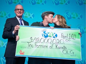 OLG's senior vice president of Lottery Greg McKenzie looks on as lottery winner Tina Ferrone of Kanata and  husband Liam McGee celebrate with a kiss after Tina collected a cheque for $48,000,020 in April 2014.