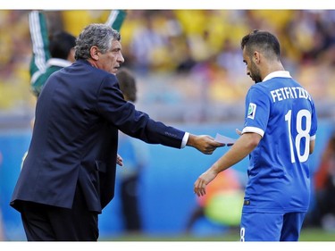 Greece's head coach Fernando Santos, left, hands a piece of paper to Greece's Giannis Fetfatzidis during the group C World Cup soccer match between Colombia and Greece at the Mineirao Stadium in Belo Horizonte, Brazil, Saturday, June 14, 2014.