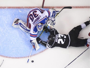 New York Rangers goalie Henrik Lundqvist, of Sweden, makes a save as Los Angeles Kings right wing Dustin Brown (23) falls during the third period in Game 5 of an NHL hockey Stanley Cup finals, Friday, June 13, 2014, in Los Angeles.
