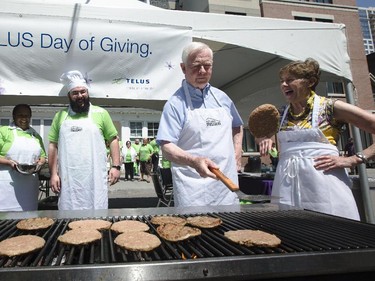 His Excellency, David Johnston, Governor General of Canada, left, flips burgers at The Ottawa Mission as part of the Telus Day of Giving as his wife, Sharon Johnston, right, looks Monday, June 2, 2014.