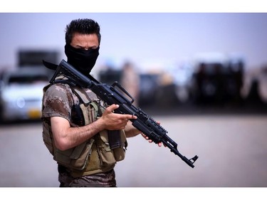 A masked Pershmerga fighter from Iraq's autonomous Kurdish region guards a temporary camp set up to shelter Iraqis fleeing violence in the northern Nineveh province, in Aski kalak, 40 kms west of the region's capital Arbil, on June 13, 2014. Thousands of people who fled Iraq's second city of Mosul after it was overrun by jihadists have been queuing in the blistering heat, hoping to enter the safety of the nearby Kurdish region and furious at Baghdad's failure to help them.